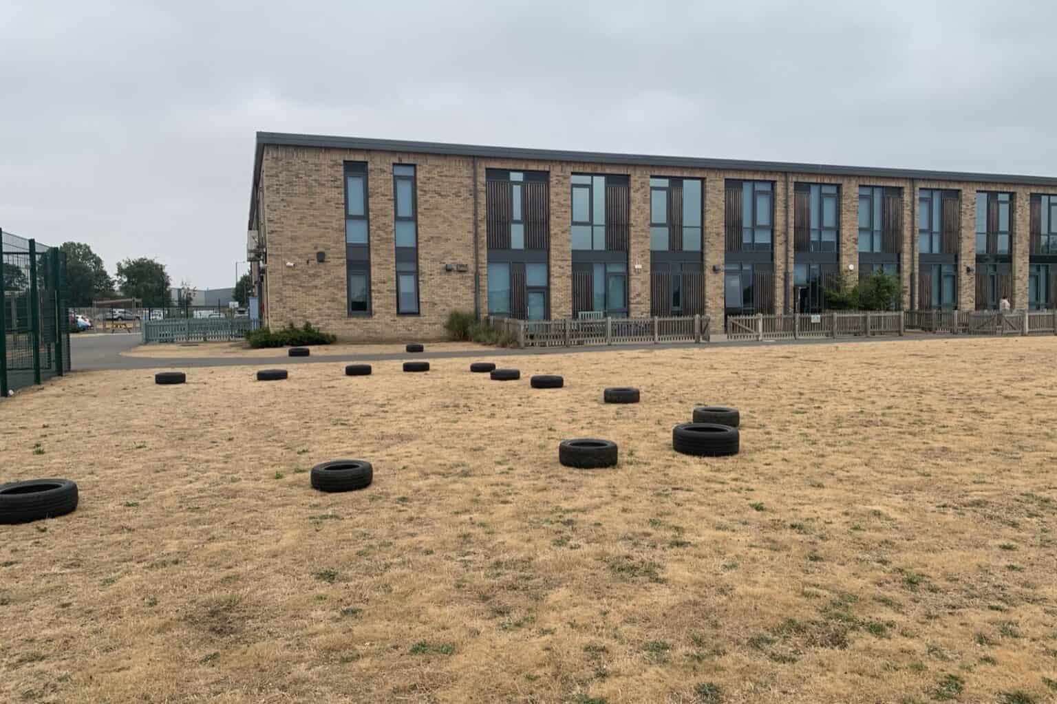The school field at Bader Academy, with the existing fenced games area beside the school building