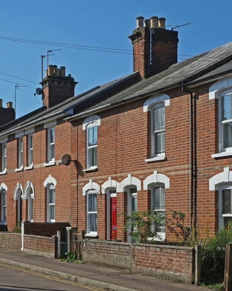 A row of Victorian red-brick terraced houses with bay windows opening onto the pavement