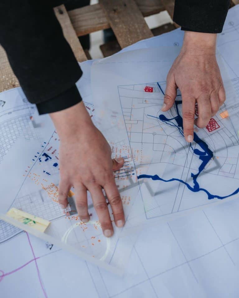 A planner marking up layered site plans and technical drawings during a planning review