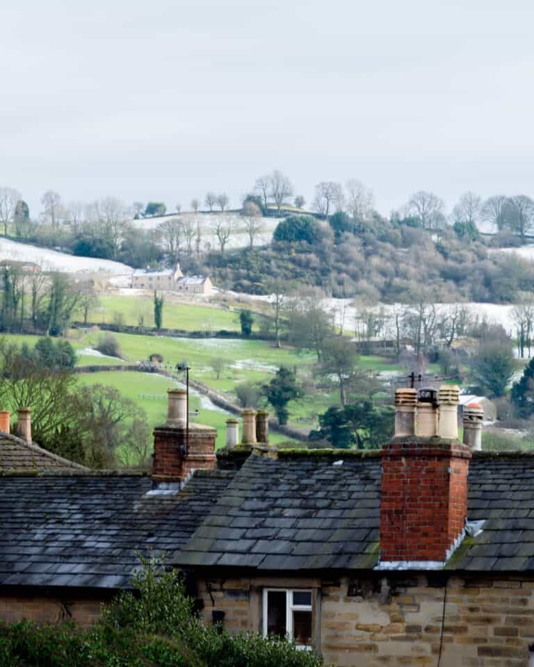 Stone rooftops and chimneys in Wirksworth with the limestone valley rising behind